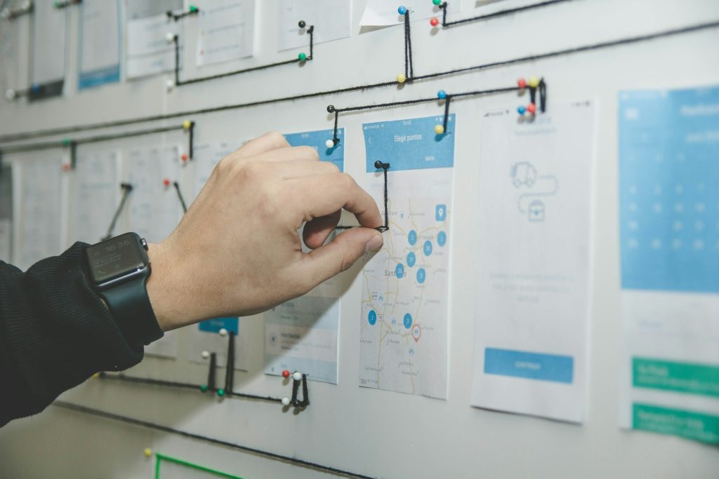 Designer arranging UX wireframes and user flows on a wall